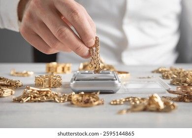 En person väger guldsmycken på en liten digital våg.